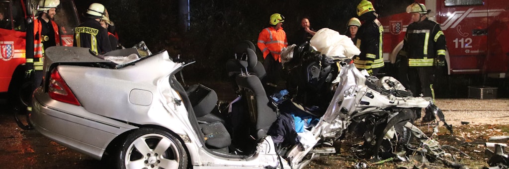Rettungskräfte stehen nach einem Autounfall an einem zerstörten PKW. Zwei Männer starben, als sie mit ihrem Wagen im Vetschauer Ortsteil Ogrosen gegen einen Baum prallten