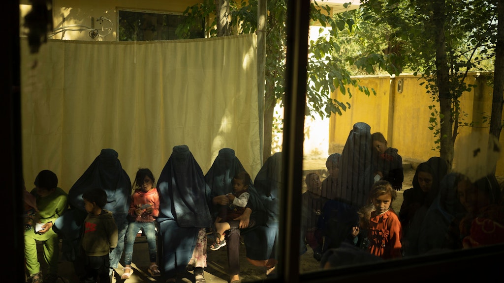 Frauen, in Burkas eingemummelt, warten mit ihren Kindern vor dem Krankenhaus auf Behandlung.