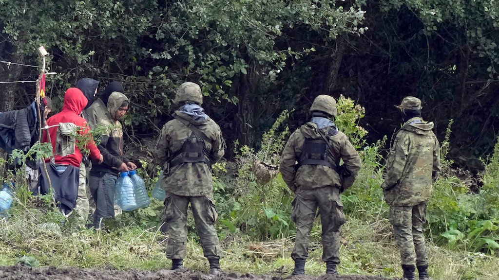 Das Bild vom 1. September 2021 zeigt drei Mitglieder des polnischen Militärs in Uniform, die an der polnisch-belarussischen Grenze auf Migranten treffen. Polen will die Zahl der Soldaten an seiner Grenze zu Belarus auf rund 10 000 erhöhen.