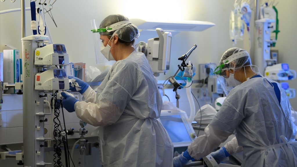 Intensivpflegerinnen sind in Schutzkleidungen auf der Covid-19-Intensivstation einer Klinik mit der Versorgung von Corona-Patienten beschäftigt. 