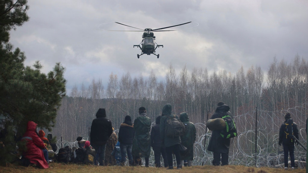 Ein polnischer Militärhubschrauber fliegt über eine Gruppe Migranten, die sich auf belarussischer Seite versammelt haben. 