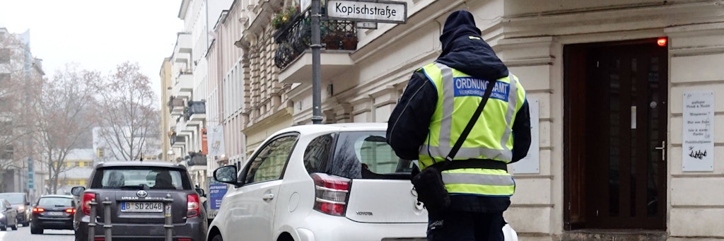 Ein Mitarbeiter des Ordnungsamtes schreibt in Berlin einen Falschparker auf.