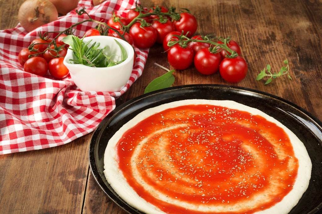 Die Sauce auf Pizza unbedingt dünn auftragen. 