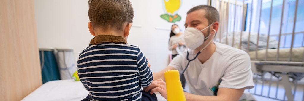 Ein Arzt untersucht in einer Kinderklinik ein Kind. 