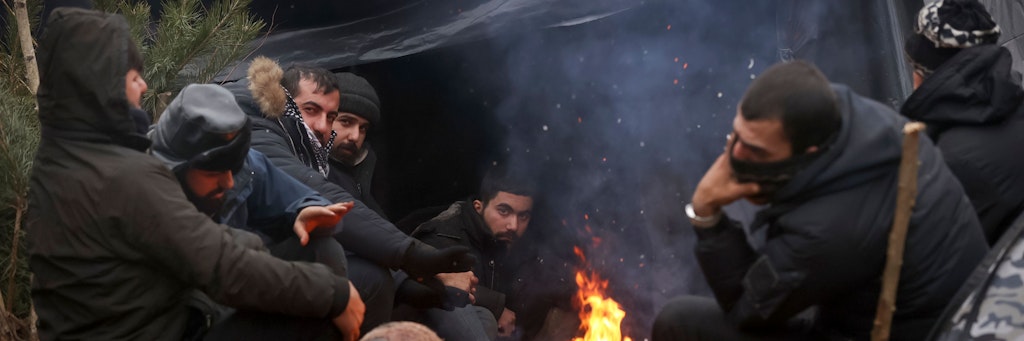Migranten wärmen sich an der belarussisch-polnischen Grenze an einem Feuer auf. 