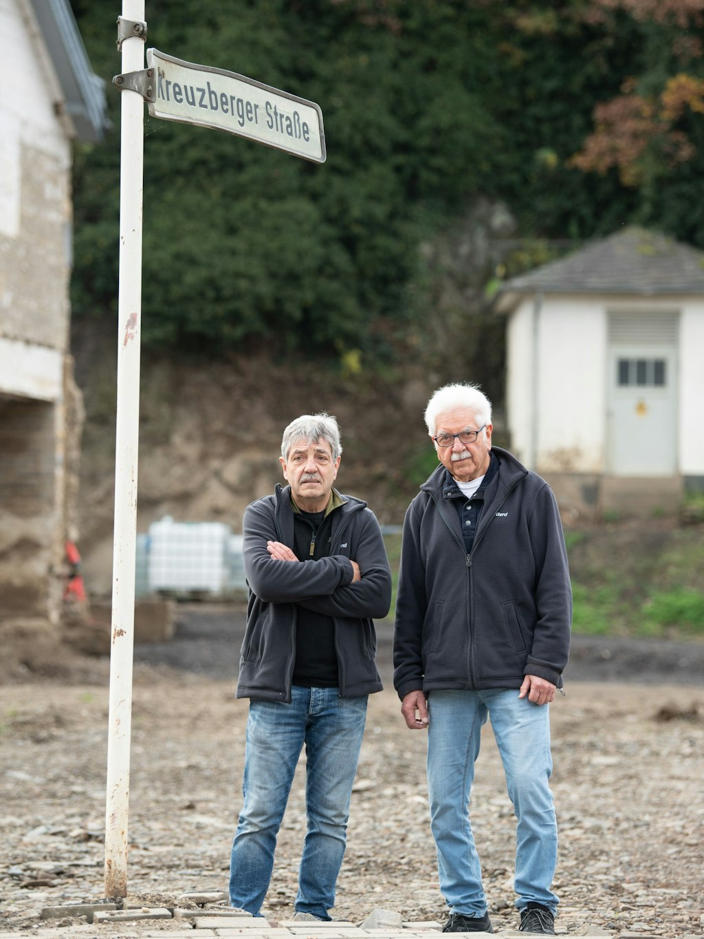 Die Brüder Bernd (li.) und Gerd Gasper stehen in Altenahr-Altenstadt an auf einer Brachfläche, auf der bis vor wenigen Wochen ihr Elternhaus gestanden hat. 
