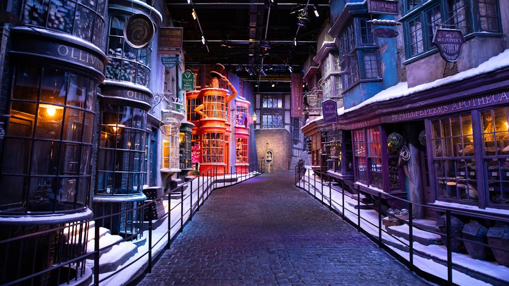 Ein Blick auf die Winkelgasse (Diagon Alley) der Warner Bros. Studios Tour London des jährlich wiederkehrenden „Hogwarts in the Snow“, bei dem die Schaufensterfronten und Bürgersteige der Winkelgasse mit Kunstschnee bedeckt sind.