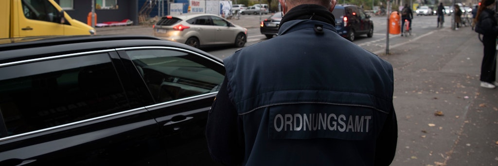 Ein Mitarbeiter des Ordnungsamtes Mitte schreibt bei einer Schwerpunktkontrolle ein Auto auf, das auf dem Bürgersteig parkt. 