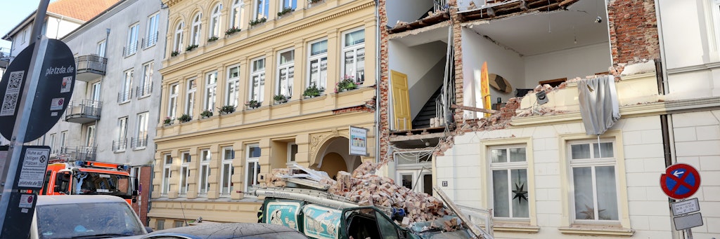 Trümmer liegen auf einem Auto vor dem Haus in Hamburg-Altona, dessen Fassade eingestürzt ist. 