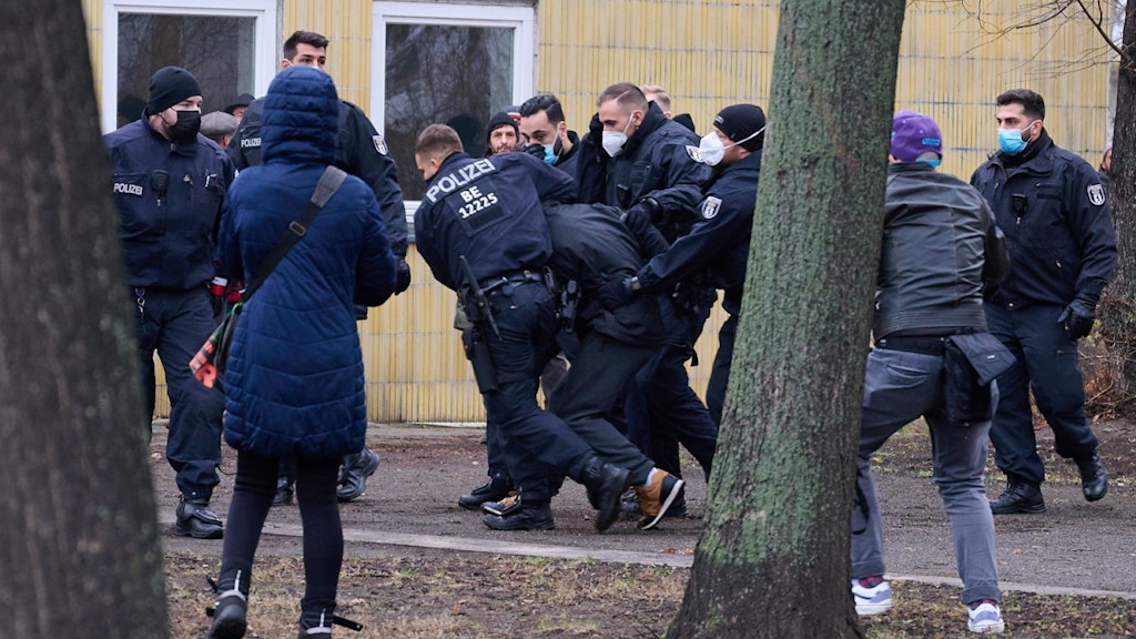 Ein Demonstrant wird von Polizisten neben der Karl-Marx-Allee festgesetzt.