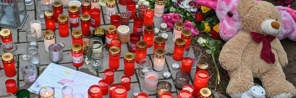 Viele Kerzen brennen vor auf einem Gehweg vor einem Einfamilienhaus.