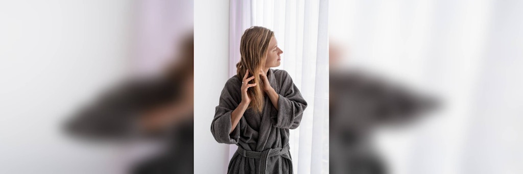 Eine Frau streicht sich durch die Haare. Fettige Haare sind für viele Menschen ein Problem.
