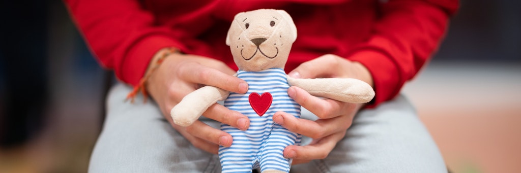 Eine Junge hält im Wartebereich eines mobilen Impfzentrums für Kinder ein Stofftier. 