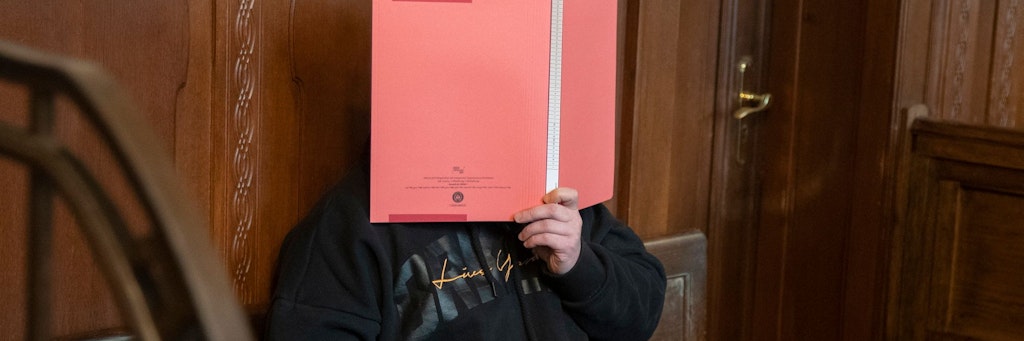 Der angeklagte Mariusz T. (41) hält sich auf der Anklagebank einen Ordner vor sein Gesucht.