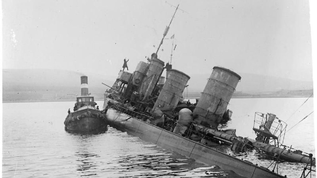 Ein Schlepper hat an einem 1919 in Scapa Flow auf Grund gesetzten deutschen Zerstörer festgemacht.