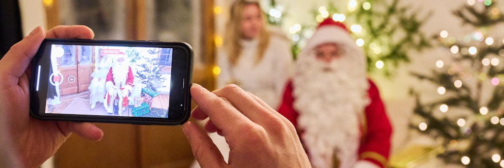 Ein Weihnachtsmann zeichnet zusammen mit seinem Engel eine personalisierte Botschaft für eine Familie auf. Wegen der Pandemie ist eine persönliche Bescherung nur eingeschränkt möglich.