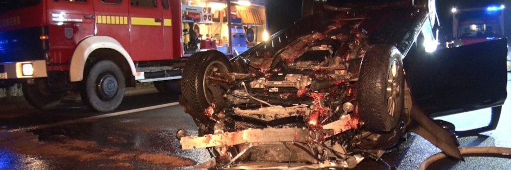 Feuerwehrleute arbeiten auf der Autobahn A31 an einem auf dem Dach liegenden Auto. Ein freilaufendes Pferd auf der Autobahn hat in der Nacht zu Dienstag mehrere Unfälle und eine Sperrung der A31 in Niedersachsen ausgelöst.