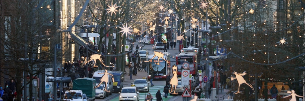 Passanten erledigen Einkäufe in der weihnachtlich geschmückten Innenstadt. 