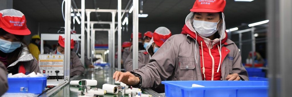 Woher kommen unsere Waren? Chinesen arbeiten in einer Fabrik am Fließband.