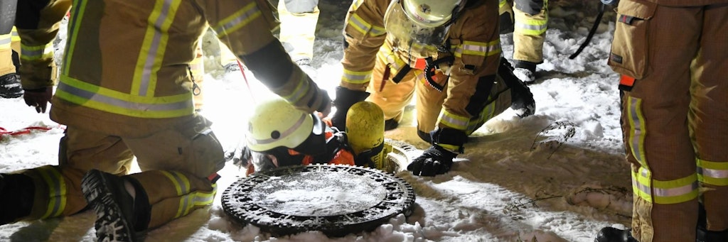 Abwärts: Ein Feuerwehrmann steigt an der Motzener Straße in einen Schacht, um in der Tiefe ein Leck im Abwasserkanal zu stopfen.