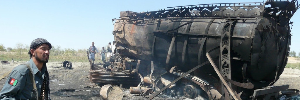 Ein afghanischer Polizist 2009 vor dem ausgebrannten Wrack eines der beiden bombardierten Tankwagen.