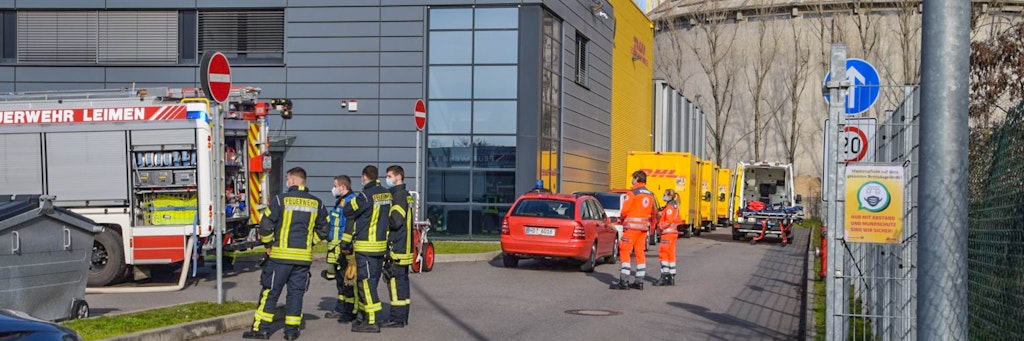 Einsatzkräfte der Feuerwehr stehen vor dem Logistikzentrum in Leimen.