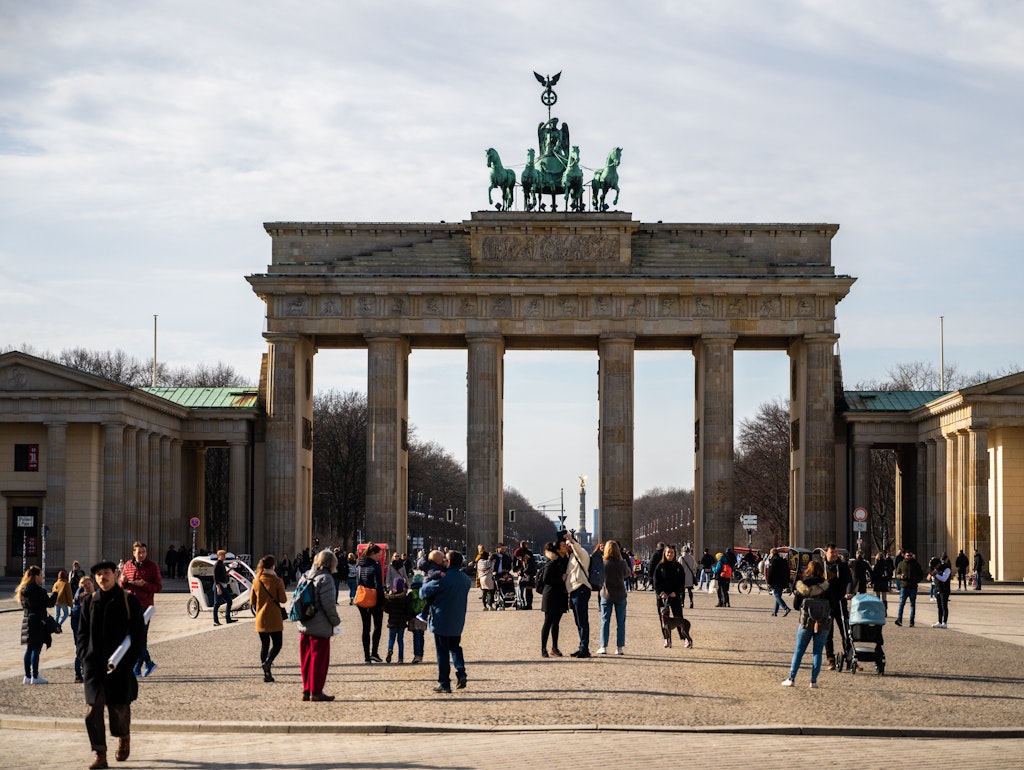Menschen genießen vor dem Brandenburger Tor die Sonne.