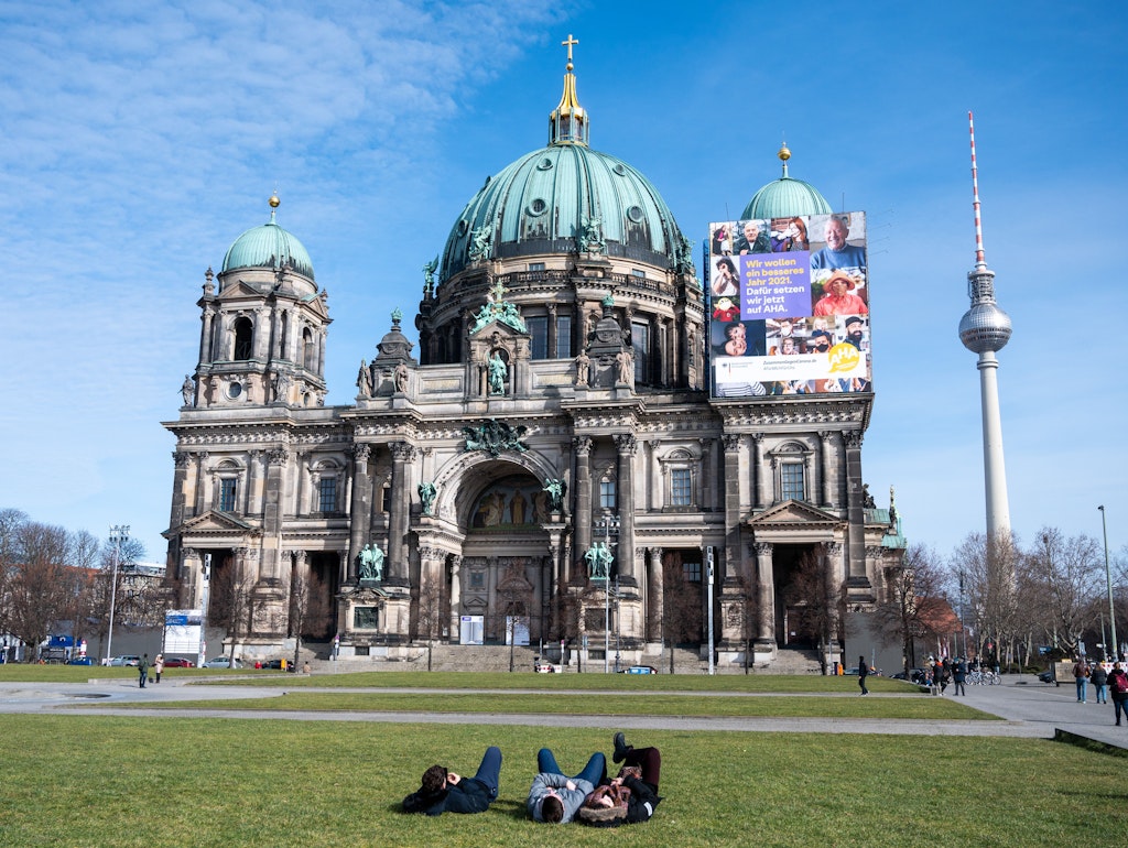 Menschen genießen im Lustgarten vor dem Berliner Dom die Sonne.