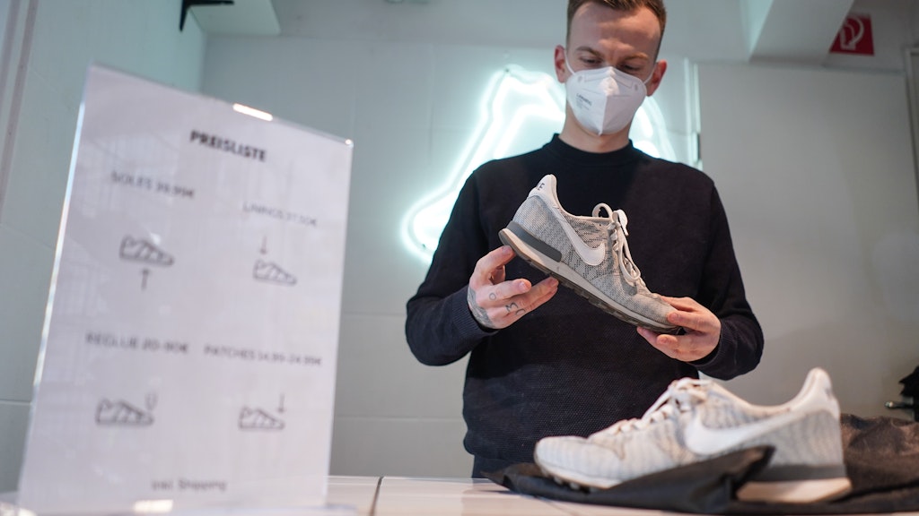 Hagen Matuszek begutachtet ein Paar Sneaker in der Reparatur-Annahmestelle von Sneaker Rescue. 