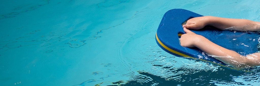 Schüler schwimmt mithilfe von Schwimmbrett.
