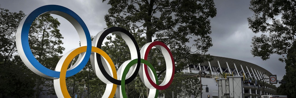 Ein Monument mit der Darstellung der Olympischen Ringe leuchtet vor dem Nationalstadion Japans. 