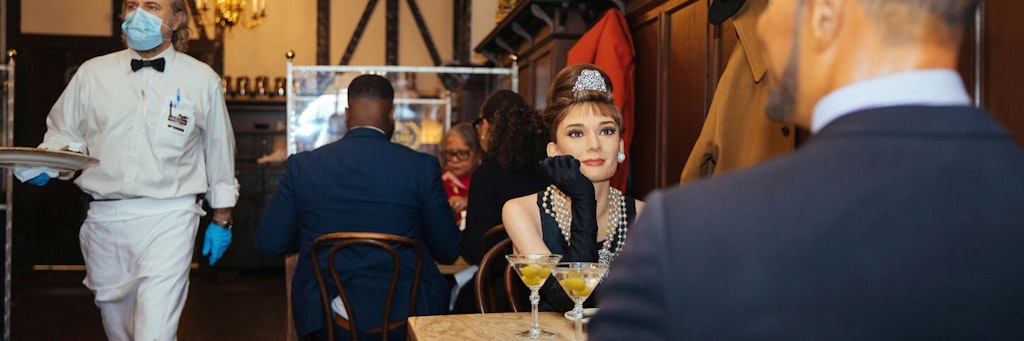 Wachsfiguren der Schauspielerin Audrey Hepburn und des Moderators Michael Strahan (rechts) besetzen einen Tisch im Peter Luger Steakhouse in Brooklyn.