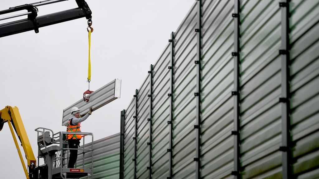 Bauarbeiter errichten einen Lärmschutz an der Baustelle zum Wiederaufbau der Dresdner Bahn am Bahnübergang Wolziger Zeile. 