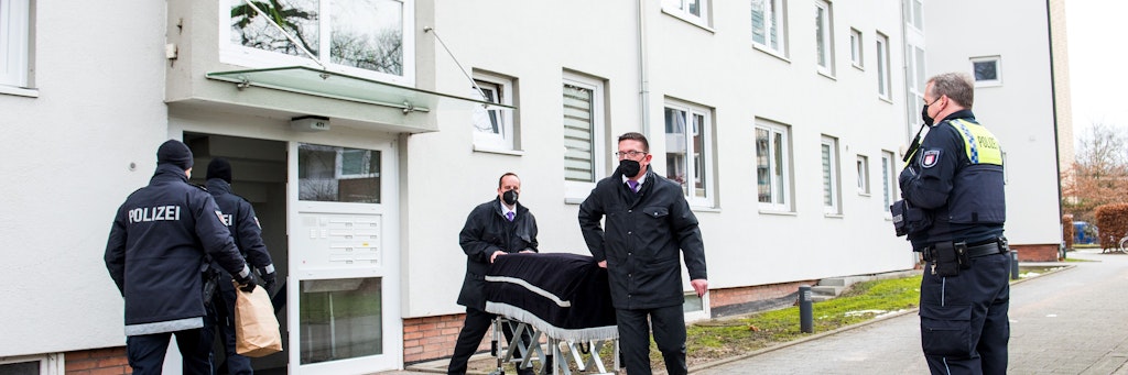 Bestatter transportieren unter Aufsicht der Polizei eine Leiche vom Tatort in Hamburg ab.