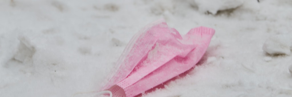 09.02.2021, Berlin: Eine pinke Maske liegt im Schnee am Bahnhof Zoo. 