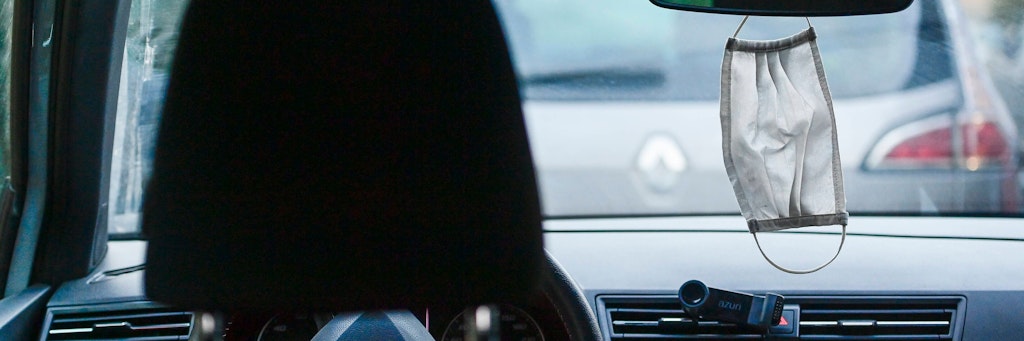 Eine Maske hängt am Rückspiegel eines Autos (Symbolbild).