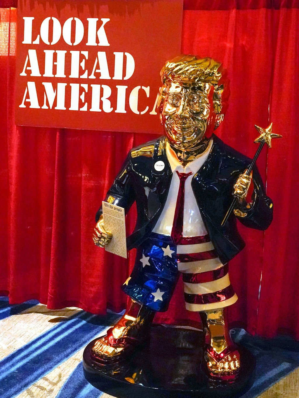 Zauberstab in der linken, Verfassung in der rechten Hand, gewandet in Stars and Stripes: Der güldene Donald.
