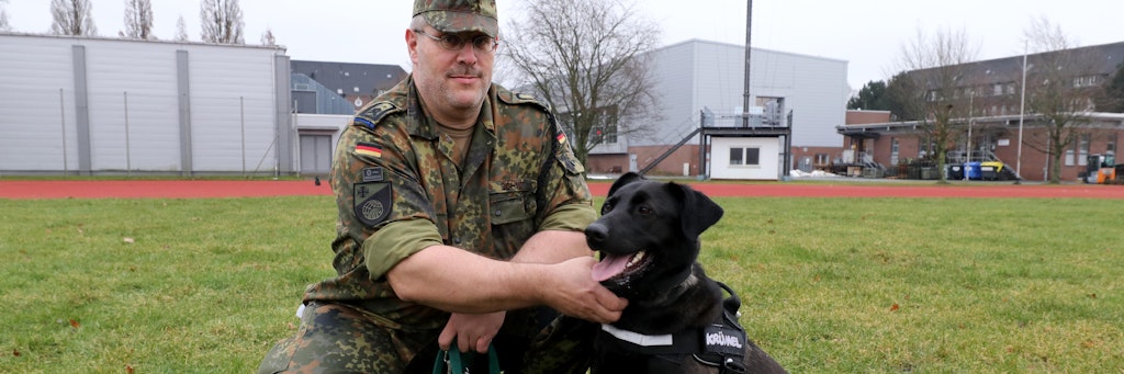 Hauptfeldwebel Alexander Schmidt mit Therapiehund Krümel an der Leine. 