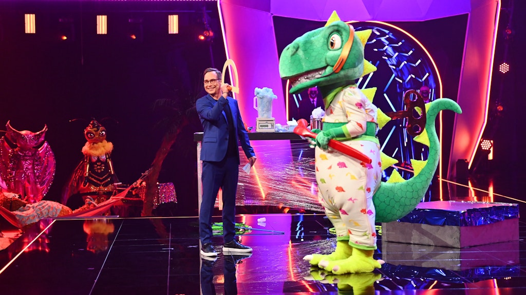 Der Dinosaurier mit Moderator Matthias Opdenhövel auf der „Masked Singer“-Bühne.