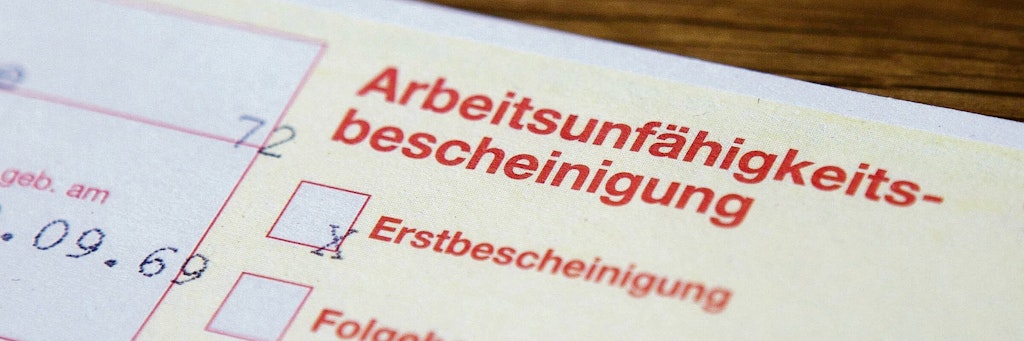 Arbeitsunfähigkeitsbescheinigung liegt auf Tisch. (Symbolfoto)