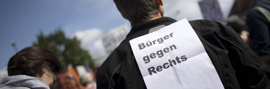 Ein Mann trägt einen Zettel mit Bürger gegen Rechts auf dem Rücken.
