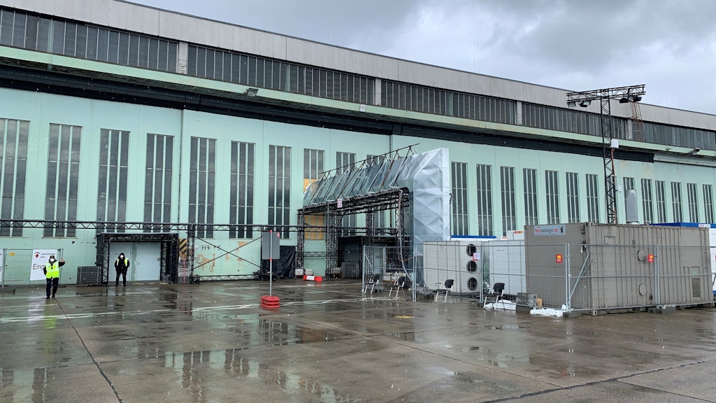 Vor dem Impf-Hangar in Tempelhof wurden große Heiz- und Belüftungsanlagen aufgestellt. Der schwarze Streifen über den Rolltoren ist der Taubenschutz.