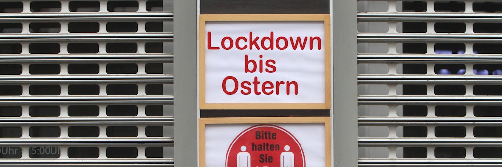 FOTOMONTAGE Schild mit Aufschrift Lockdown bis Ostern an einem mit Rolltor verschlossenen Geschäfts in der Innenstadt von Frankfurt, Hessen, Deutschland *** PHOTOMONTAGE Sign saying Lockdown until Easter on a shuttered store in downtown Frankfurt, Hesse, Germany