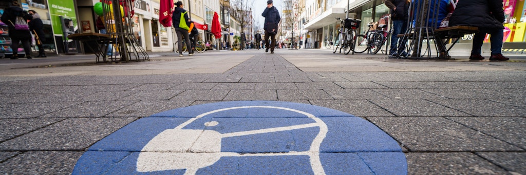 Ein Symbol zur Maskenpflicht ist auf dem Pflaster der Fußgängerzone in der Offenbacher Innenstadt aufgebracht. Die Stadt liegt seit Tagen bei einer Corona-Inzidenz über der Marke von 200.