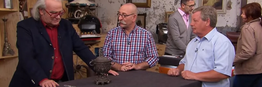 Szene aus Bares für Rares: Kunstexperte Albert Maier, Moderator Horst Lichter und Kandidat Jürgen Tesch machen sich über den antiken Pokal her.