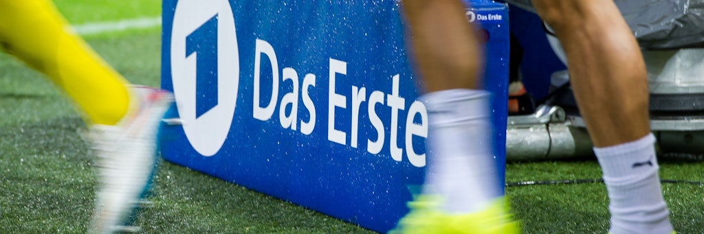 Spieler laufen vor einer TV- Kamera der ARD auf das Spielfeld.