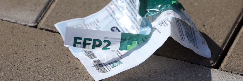Die Verpackung einer FFP2-Atemschutzmaske liegt auf einem Parkplatz