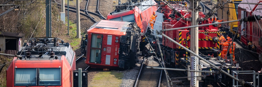 Eine Lokomotive ist umgekippt, dahinter stehen zwei schief. Der Bergungskran ist rechts zu sehen.