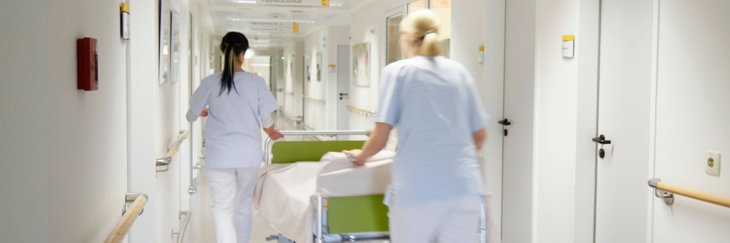 Krankenschwestern schieben ein Krankenbett.