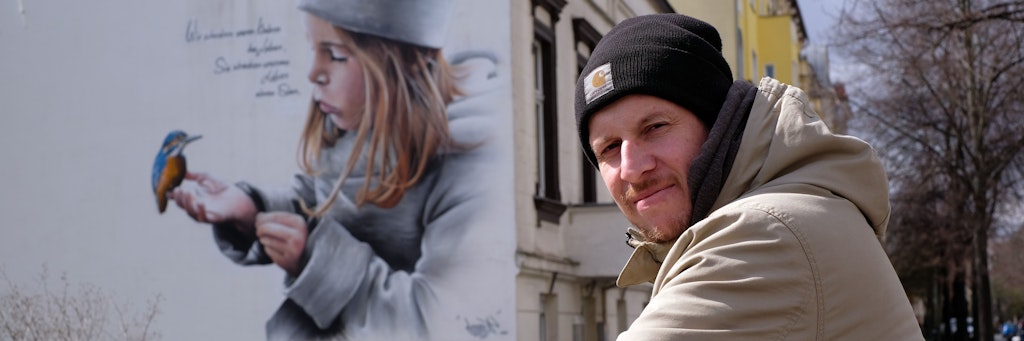 Rico Mau vor einem Bild, das seine Tochter zeigt. „Wir schenken unseren Kindern das Leben, sie schenken unserem Leben einen Sinn“ steht neben dem Portrait. <br><br>